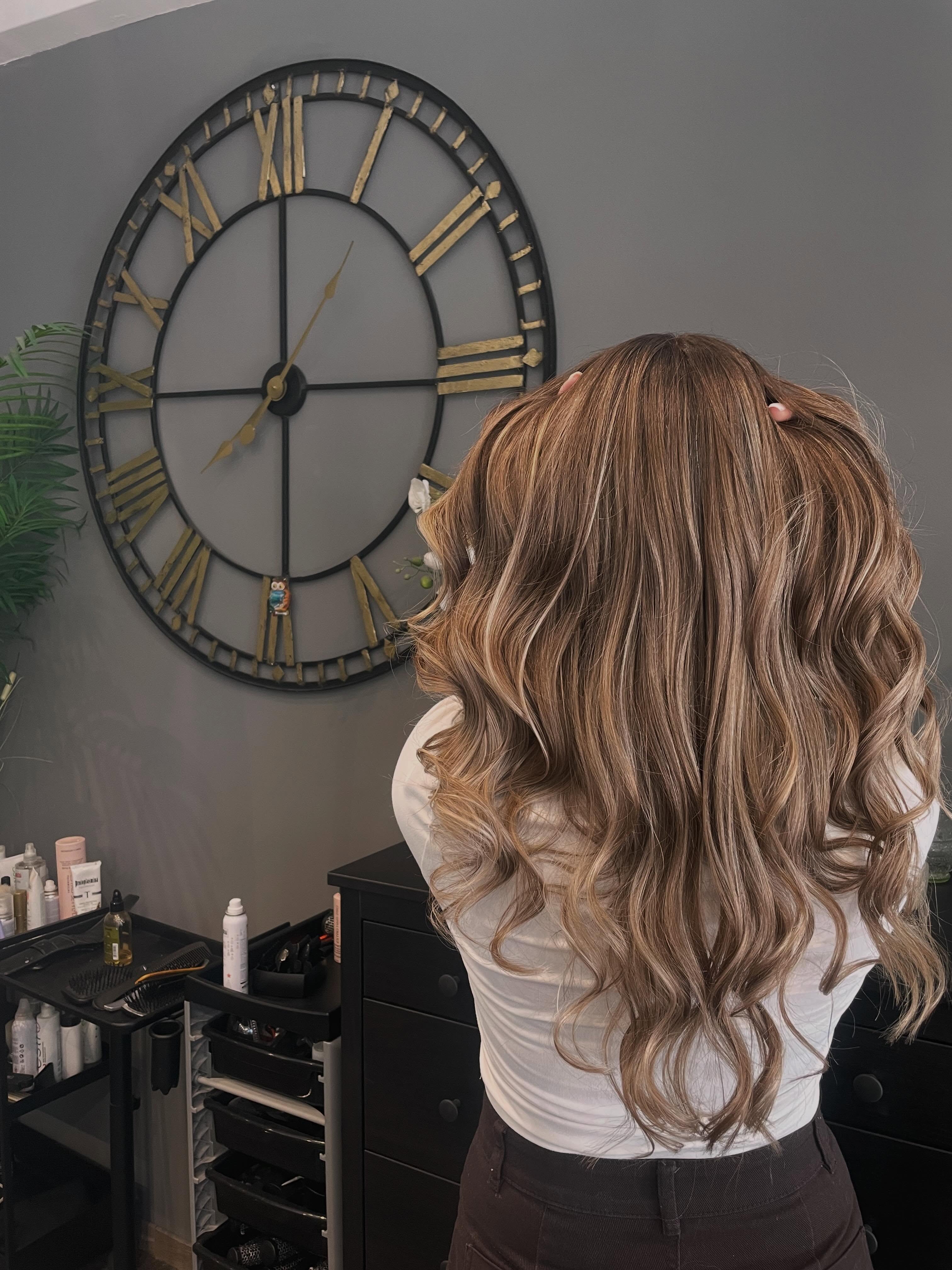 Capelli castani con riflessi dorati davanti al grande orologio con numeri romani del salone